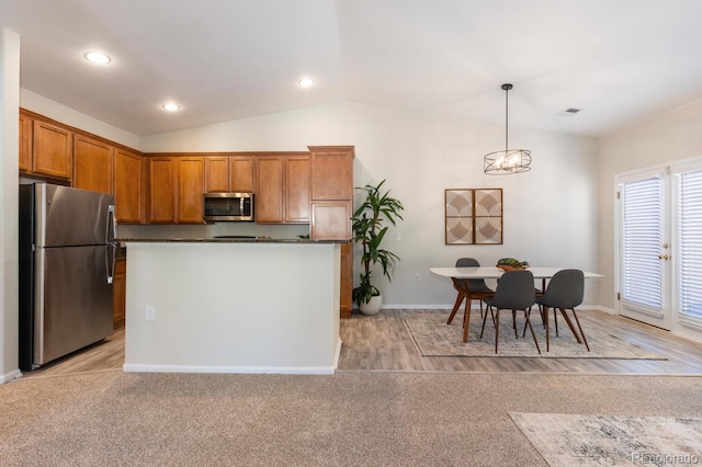 kitchen featuring decorative light fixtures, light carpet, appliances with stainless steel finishes, and lofted ceiling