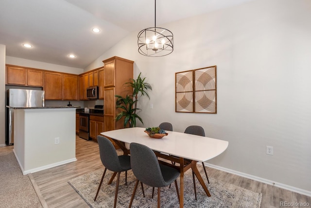 dining space featuring an inviting chandelier, lofted ceiling, and light hardwood / wood-style floors