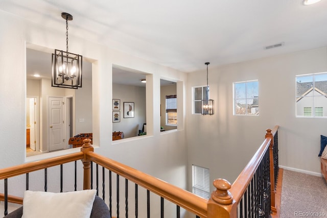 hallway with carpet floors and a notable chandelier