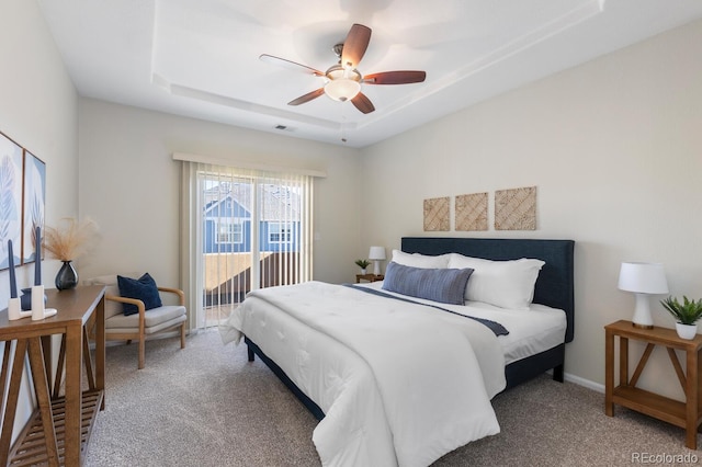 carpeted bedroom with ceiling fan and a tray ceiling