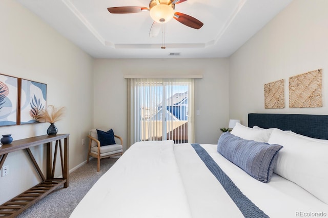 carpeted bedroom featuring a raised ceiling and ceiling fan