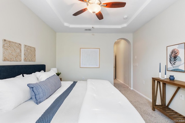 bedroom featuring a raised ceiling, ceiling fan, and carpet flooring