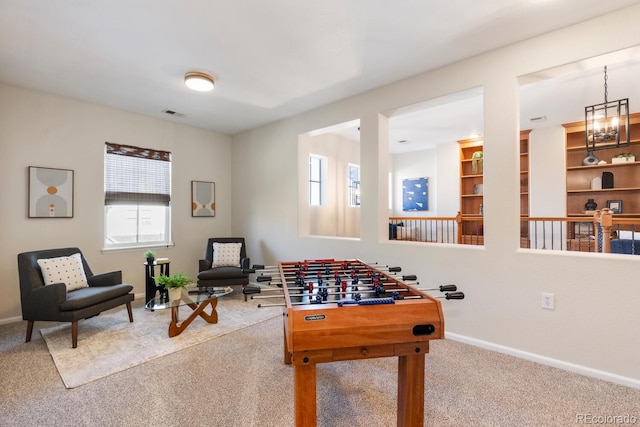 recreation room featuring a notable chandelier and carpet flooring