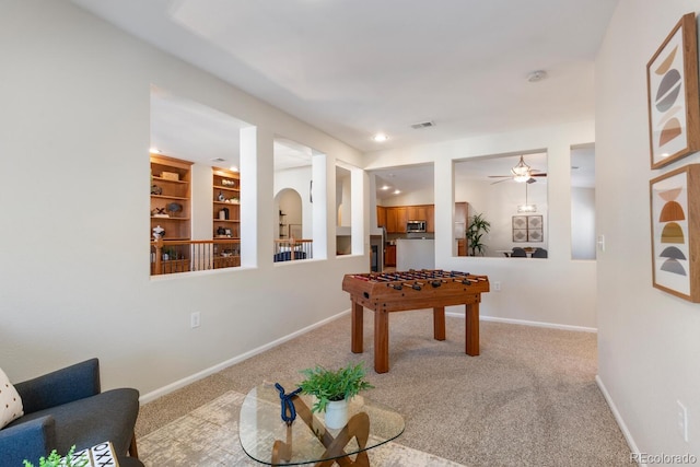 playroom featuring light carpet, ceiling fan, and built in features