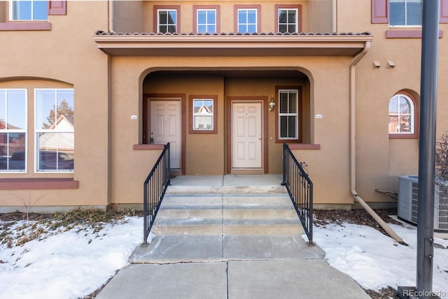 snow covered property entrance featuring central AC unit