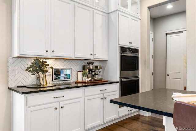 kitchen with double oven, backsplash, dark hardwood / wood-style floors, and white cabinets