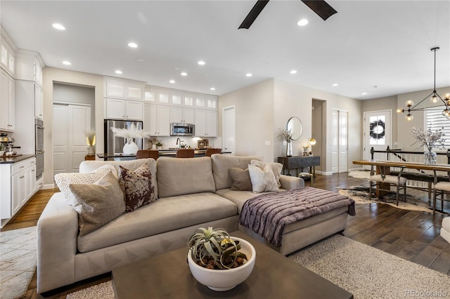 living room with dark wood-type flooring and ceiling fan with notable chandelier