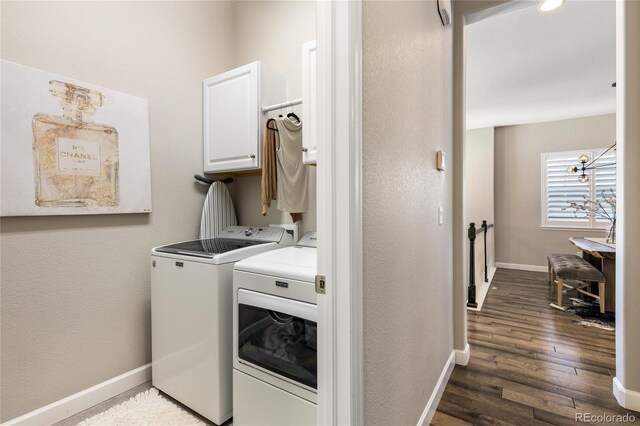 laundry room featuring baseboards, cabinet space, wood finished floors, and washing machine and clothes dryer
