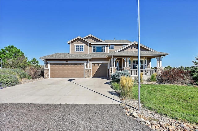 craftsman-style home with driveway, stone siding, a porch, a front yard, and a garage