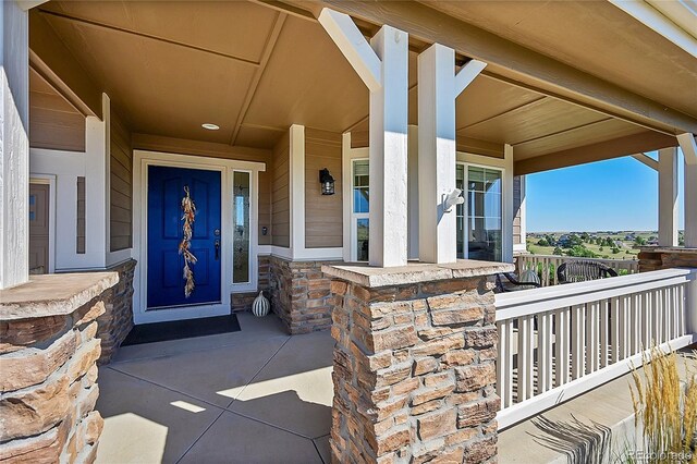 entrance to property with a porch and stone siding