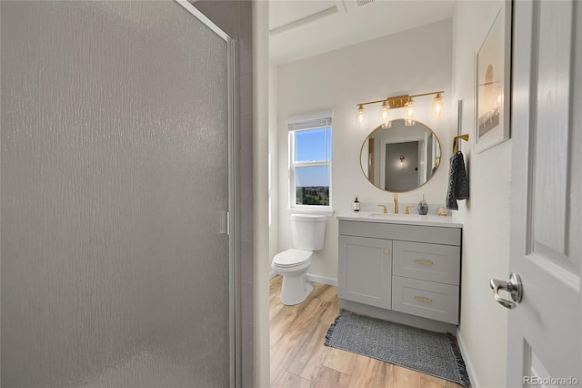 bathroom with toilet, a stall shower, wood finished floors, baseboards, and vanity