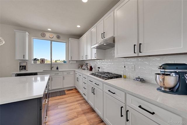 kitchen featuring light wood-type flooring, under cabinet range hood, white cabinetry, light countertops, and stainless steel gas cooktop