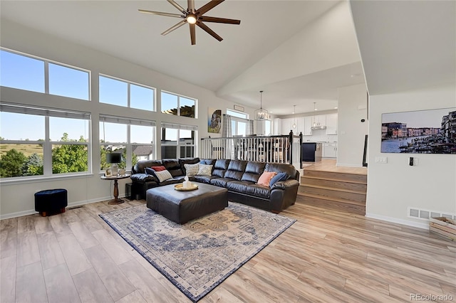 living room featuring visible vents, high vaulted ceiling, light wood-type flooring, and baseboards