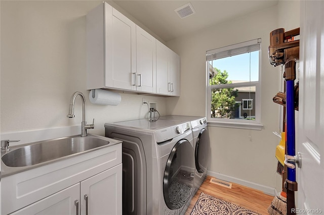 laundry area featuring cabinet space, separate washer and dryer, visible vents, and a sink