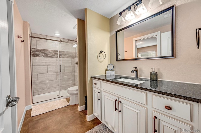 bathroom with baseboards, toilet, vanity, a stall shower, and a textured ceiling