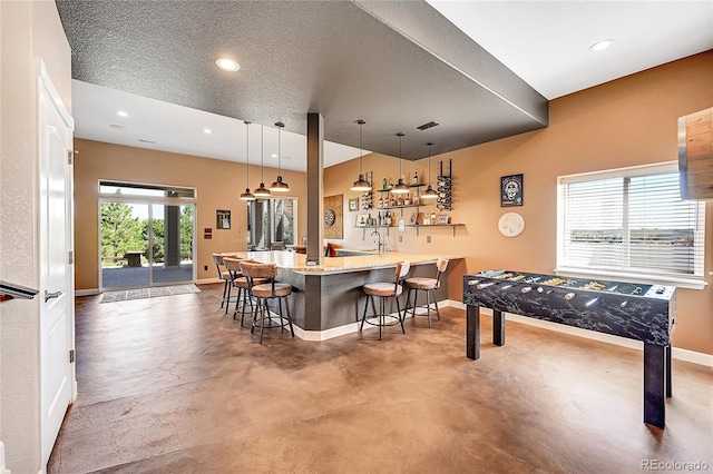 kitchen with finished concrete floors, a textured ceiling, a breakfast bar area, and baseboards