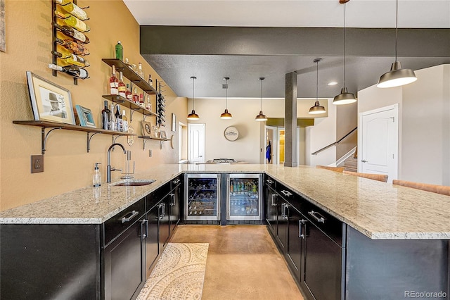 kitchen with wine cooler, dark cabinetry, and a sink