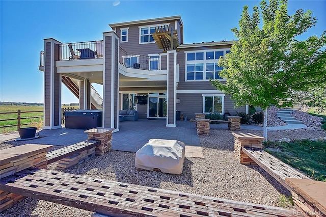 rear view of house with a balcony, a patio area, and a hot tub