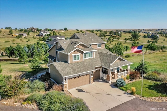 view of front of home featuring stone siding, covered porch, concrete driveway, an attached garage, and a front yard