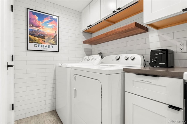 laundry area with tile walls, cabinets, washer and dryer, and light wood-type flooring