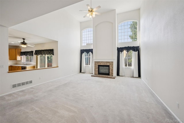 19076 E Lasalle Pl, Aurora, CO 80013 - unfurnished living room with a towering ceiling, a ceiling fan, carpet flooring, and a brick fireplace