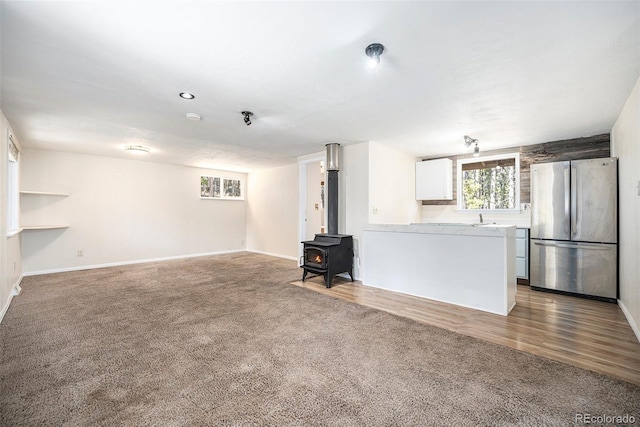 unfurnished living room with a wood stove, hardwood / wood-style floors, and sink