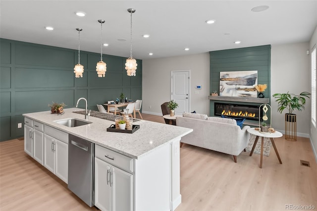 kitchen featuring sink, decorative light fixtures, a center island with sink, dishwasher, and white cabinets