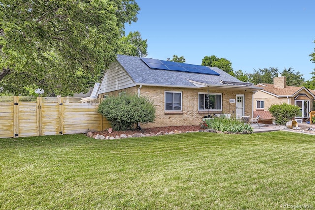 6995 W 27th Ave, Wheat Ridge, CO 80033 - view of front facade featuring brick siding, roof with shingles, roof mounted solar panels, and a patio