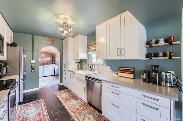 6995 W 27th Ave, Wheat Ridge, CO 80033 - kitchen featuring stainless steel appliances, arched walkways, white cabinets, and light countertops