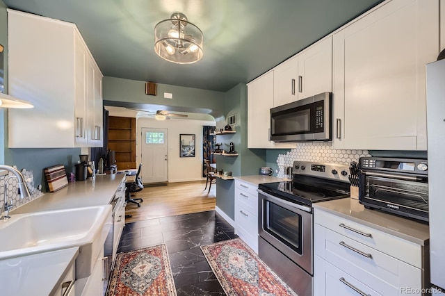 6995 W 27th Ave, Wheat Ridge, CO 80033 - kitchen with appliances with stainless steel finishes, white cabinetry, light countertops, tasteful backsplash, and dark marble finish flooring