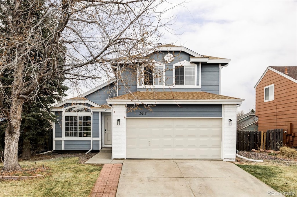 traditional-style house with brick siding, concrete driveway, an attached garage, and fence