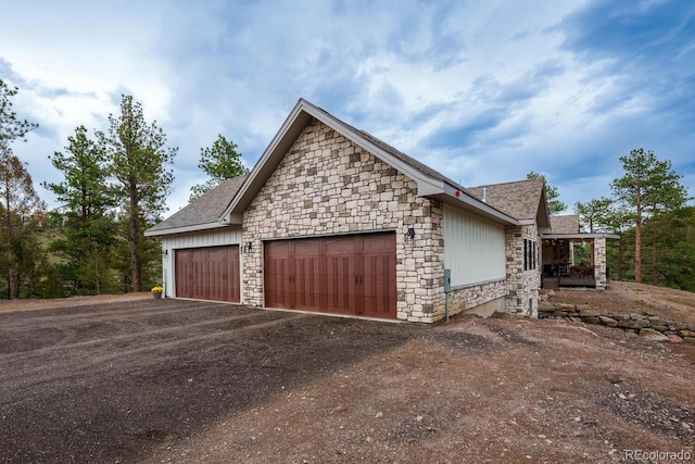 31455 Half Peak Trl, Pine, CO 80470 - view of property exterior featuring stone siding, an attached garage, and dirt driveway