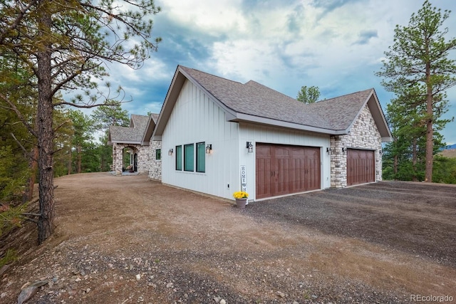 31455 Half Peak Trl, Pine, CO 80470 - view of property exterior with stone siding, driveway, a garage, board and batten siding, and a shingled roof