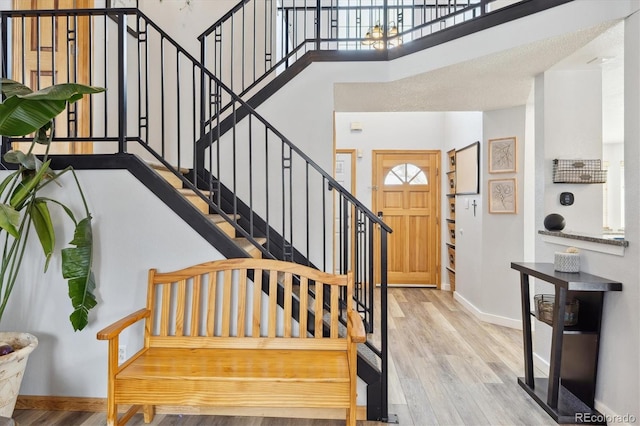 entryway featuring baseboards, a high ceiling, wood finished floors, and stairs