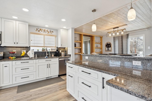 kitchen with backsplash, stainless steel dishwasher, light wood-style flooring, and white cabinetry