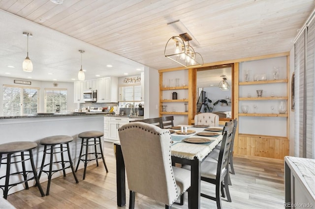 dining space featuring a wainscoted wall, wood walls, wooden ceiling, and light wood-type flooring