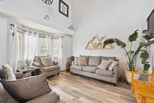 living room featuring light wood-type flooring and a towering ceiling