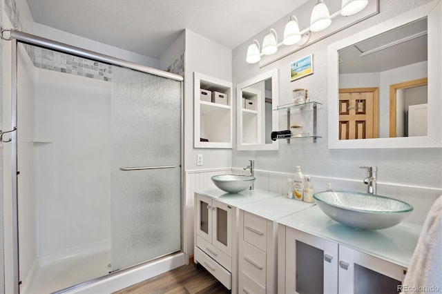 bathroom featuring a sink, double vanity, wood finished floors, and a shower stall