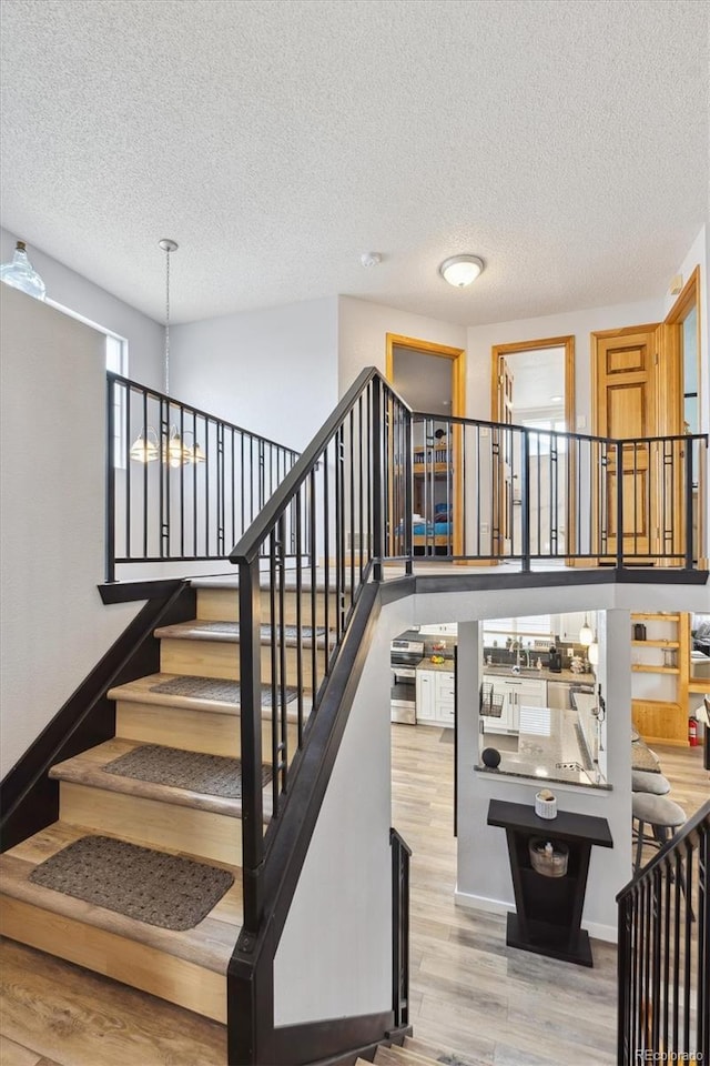 stairway featuring baseboards, a textured ceiling, and wood finished floors