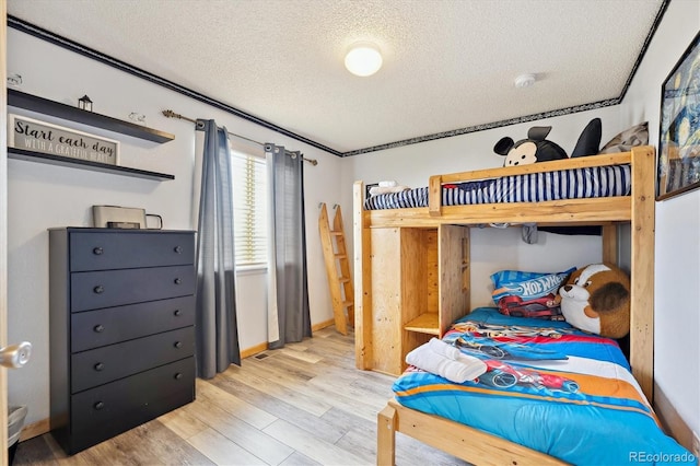 bedroom featuring a textured ceiling, baseboards, and wood finished floors