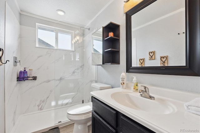 full bath featuring a marble finish shower, crown molding, toilet, and vanity