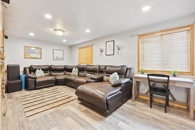 living area with recessed lighting, a textured ceiling, and light wood-style flooring