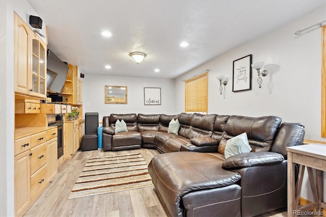 living room with recessed lighting, a textured ceiling, and light wood-style flooring