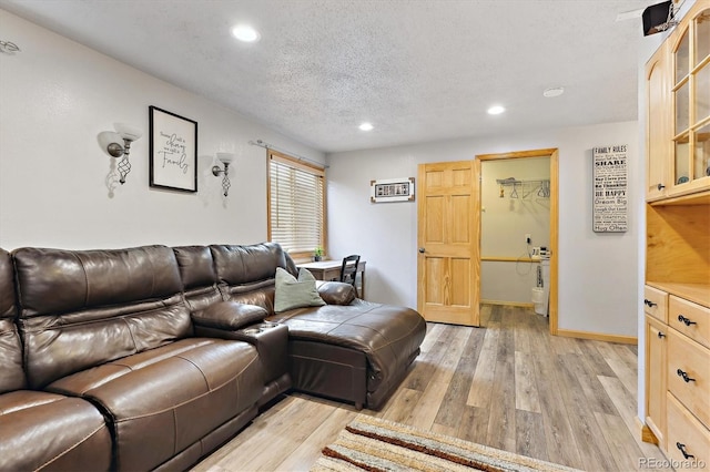 living area with recessed lighting, baseboards, a textured ceiling, and light wood finished floors