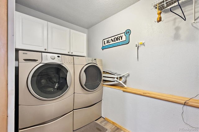 washroom with washer and clothes dryer, cabinet space, a textured ceiling, and light wood-type flooring