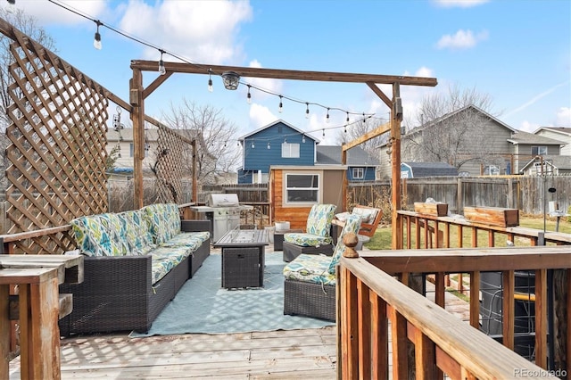 deck with an outbuilding, an outdoor living space, a fenced backyard, grilling area, and a storage shed