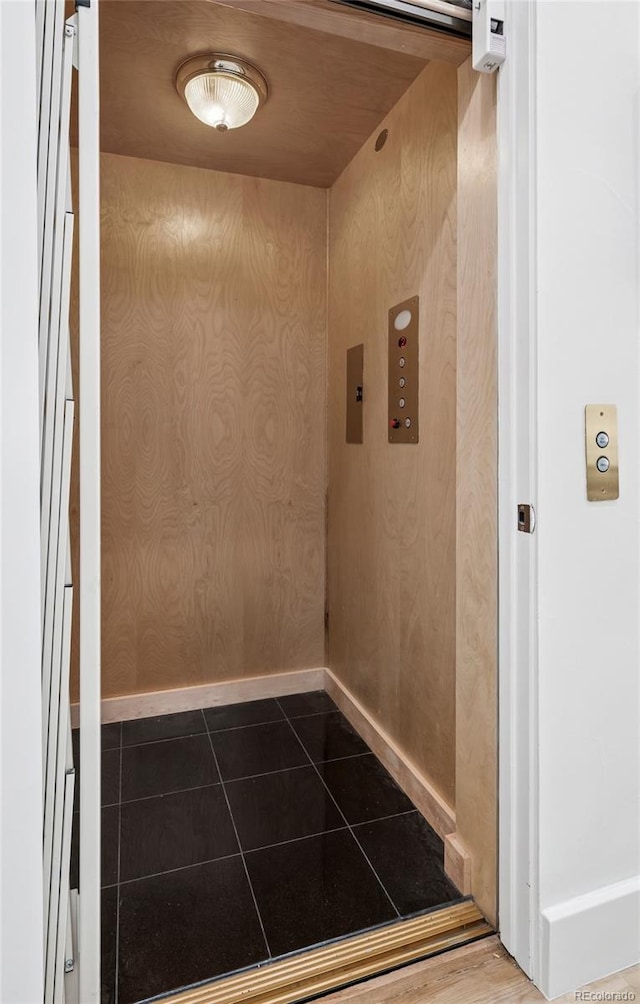 interior space featuring dark tile patterned floors, baseboards, and elevator