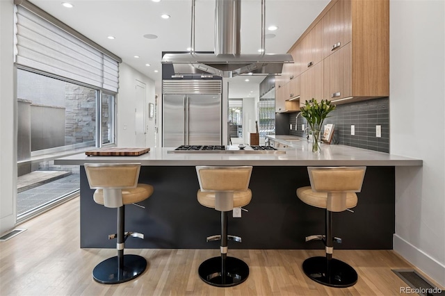 kitchen featuring light countertops, light wood-style flooring, gas stovetop, built in refrigerator, and modern cabinets