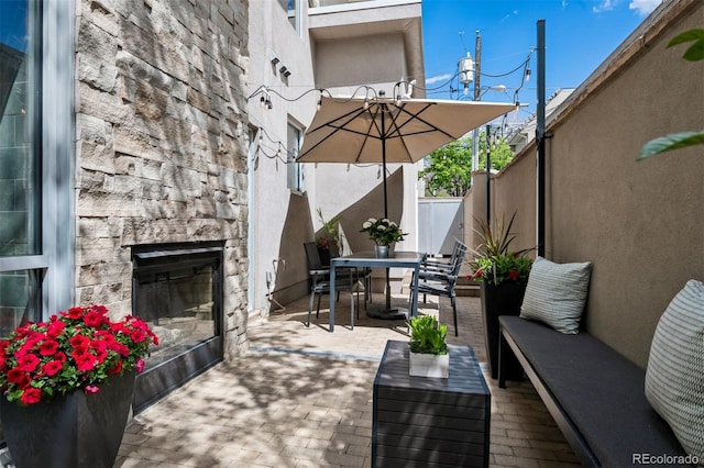 view of patio with fence, outdoor dining space, and an outdoor living space with a fireplace