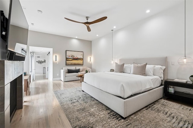 bedroom with a fireplace, light wood-style floors, ensuite bathroom, recessed lighting, and a ceiling fan